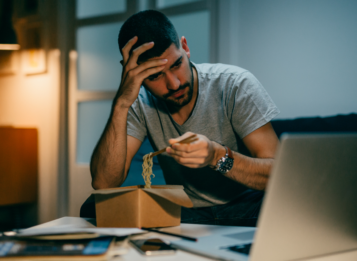 man eating late while working on laptop