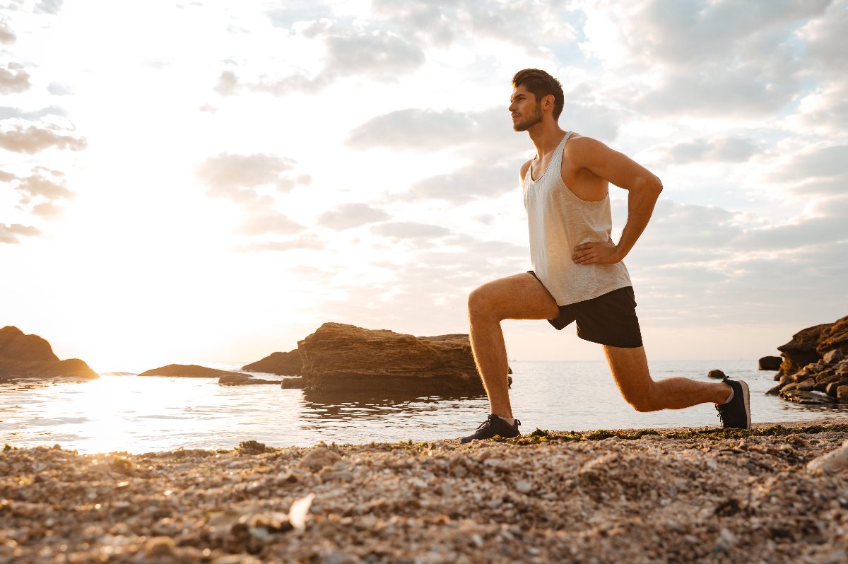 fitness man performing lunges on beach at sunset, bodyweight exercises to lose weight