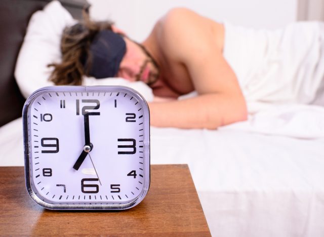 alarm clock next to man sleeping