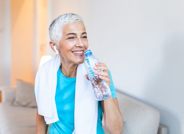 mature athletic woman drinking water bottle