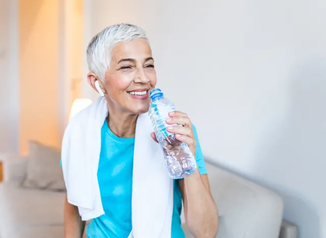 mature athletic woman drinking water bottle