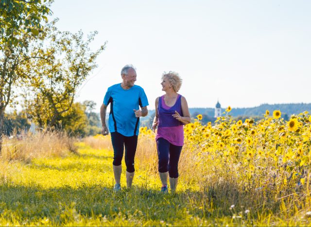 mature fitness couple running through sunny field