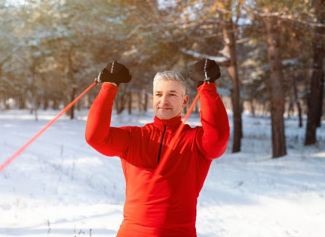 mature man in snow working out with resistance band, demonstrates exercises you shouldn't skip after 50