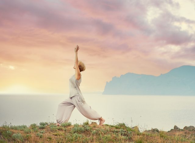 mature woman doing morning yoga in the mountains