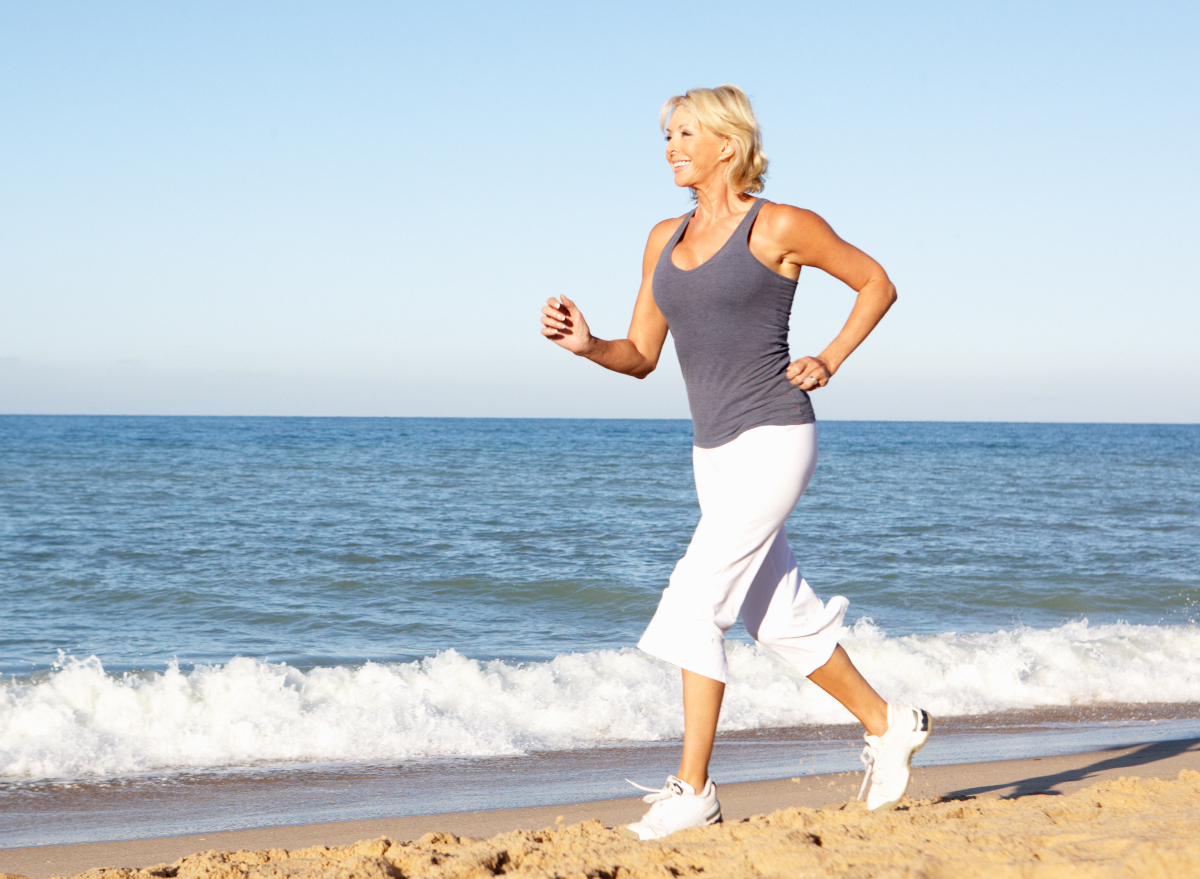mature woman running on the beach, exercise secrets to live to 100 and beyond