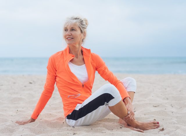middle-aged fitness woman stretching on beach demonstrating speed up weight loss as you age