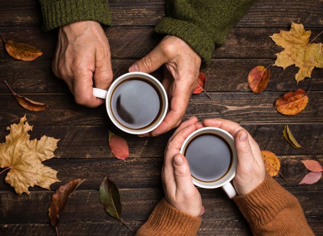 older couples hands holding mugs of coffee, autumn