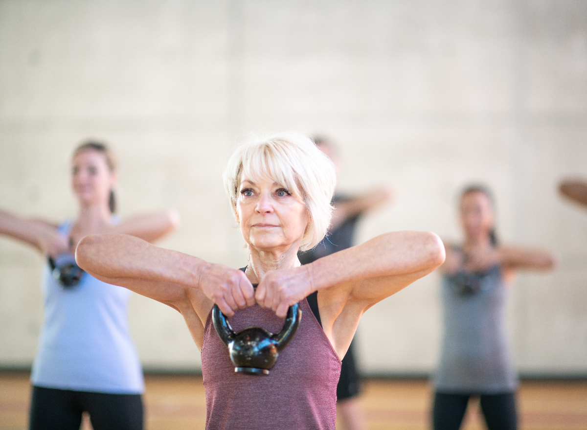 older woman lifting kettlebell, demonstrating exercises to build stronger muscles in your 60s