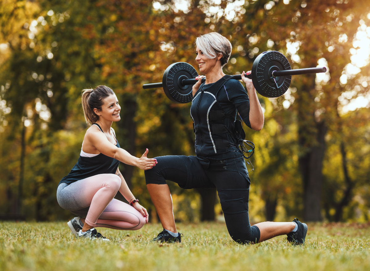 woman performing barbell squat as part of workout to shrink your FUPA