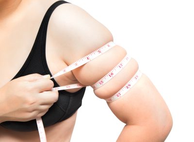 woman measuring arm fat, demonstrating exercises to lose arm fat