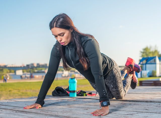 fit woman outdoors demonstrating pushup exercises to lose arm fat fast