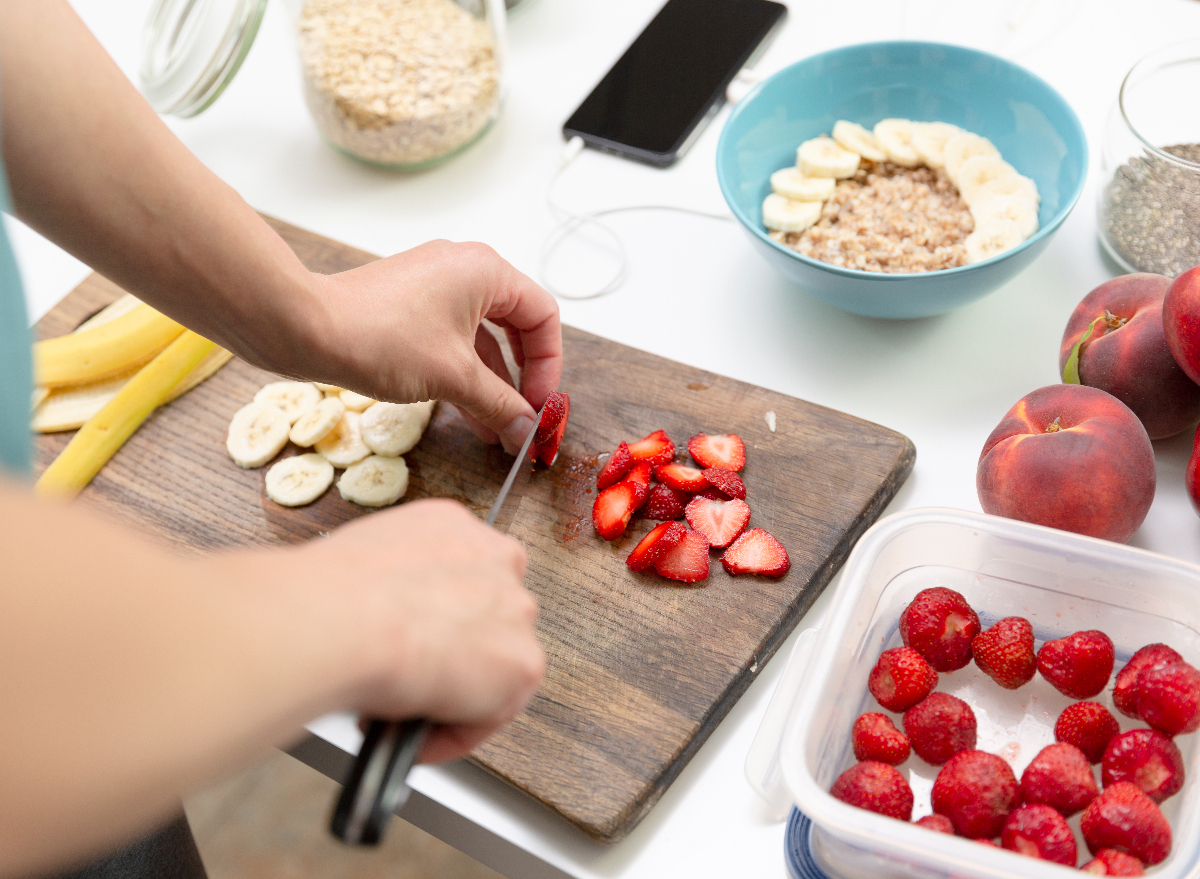 woman preparing oatmeal with strawberries, bananas, and chia seeds