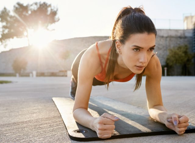 Woman doing strength training, plank outdoors