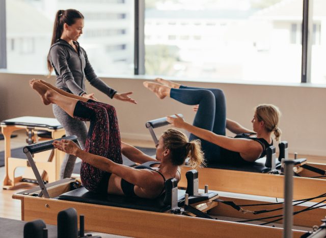 instructor instructing women on pilates reformers, workout