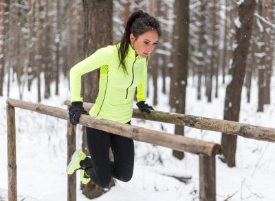 fitness woman in the snow demonstrating bodyweight dips workout to strengthen your muscles