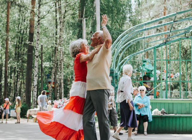 elderly couple dancing in park, demonstrating secrets to live to 100