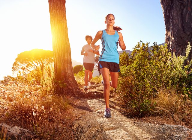 fit couple jogging on trail on a sunny day to slim down and get toned