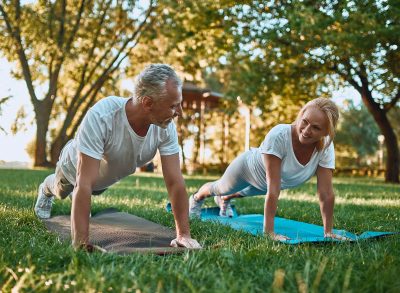 fit couple outdoors demonstrating floor workout to build lean muscle as you age