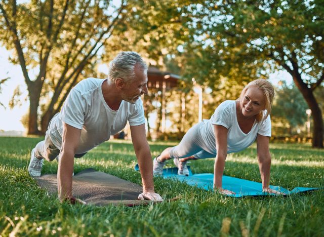 fit couple à l'extérieur faisant la démonstration d'un entraînement au sol pour développer des muscles maigres à mesure que vous vieillissez