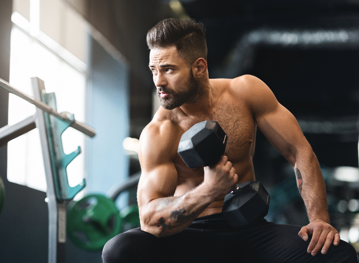 fit man at gym performing dumbbell exercises for sleeve-busting biceps