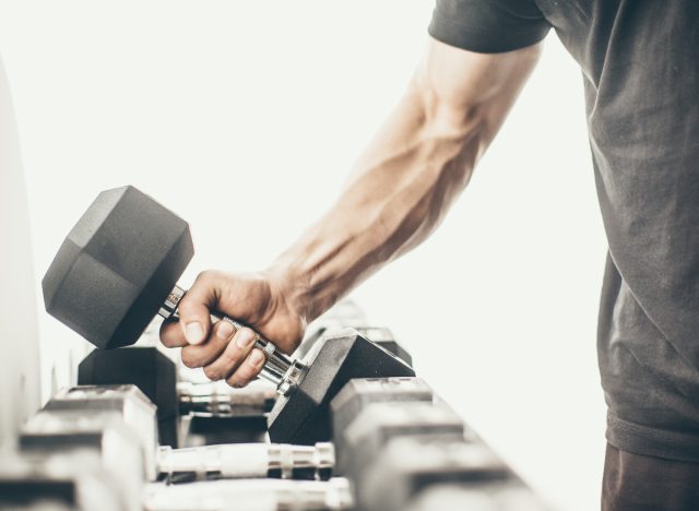 man grabs heavy dumbbell for farmer carries