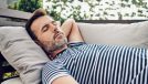 man demonstrating the benefits of napping every day on a couch outdoors