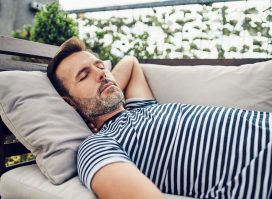 man demonstrating the benefits of napping every day on a couch outdoors