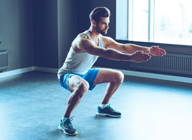 man performing squats, one of the exercises trainers do to stay fit