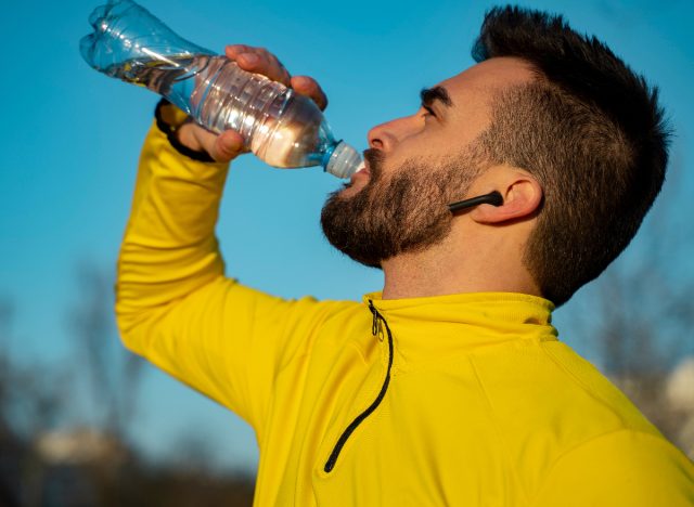 man hydrating outdoor workout, demonstrating i you should drink water while working out