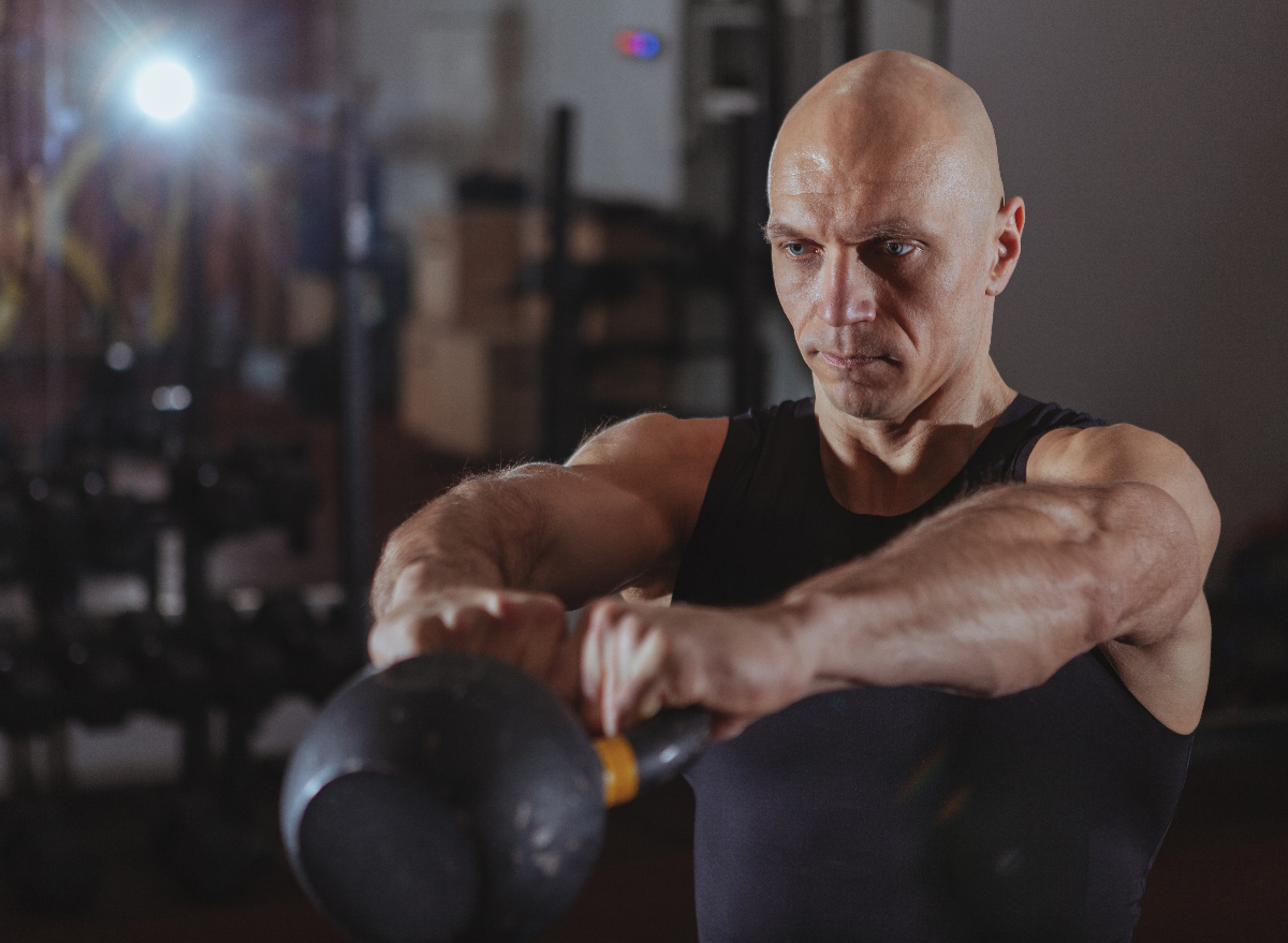 mature man with kettlebell at gym performing exercises to lose belly fat