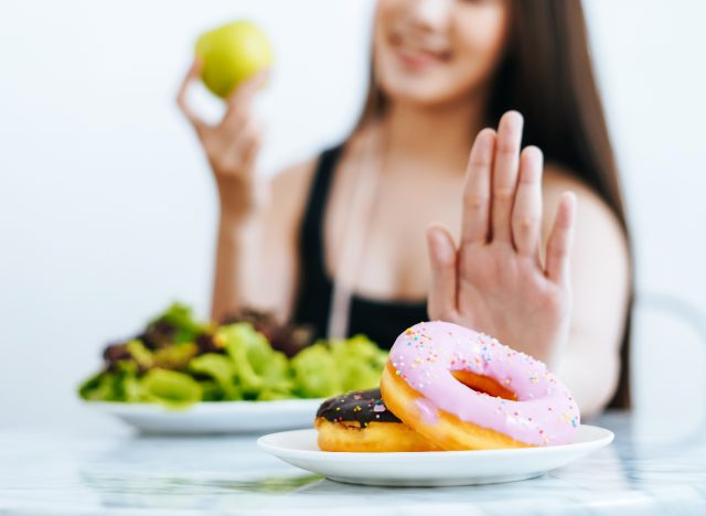 woman saying no to donuts, demonstrating how to lose body fat everywhere