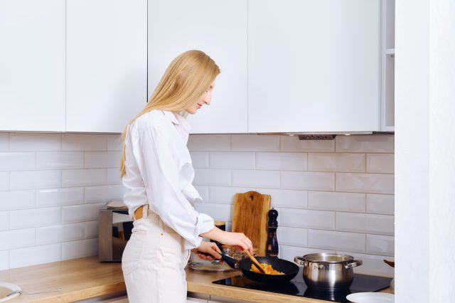 Woman stirring vegetables in a frying pan