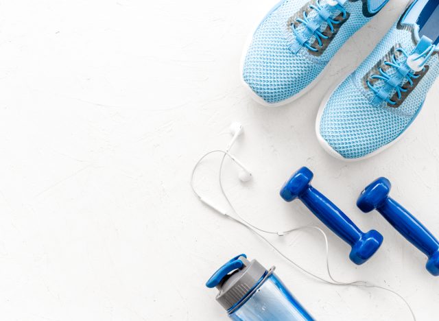 sneakers with dumbbells and water bottle, plain background
