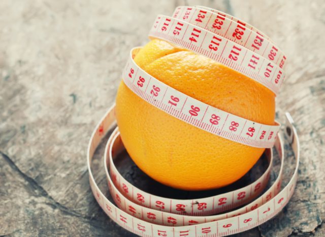 tape measure around orange, one of the best fruits to lose five inches of belly fat