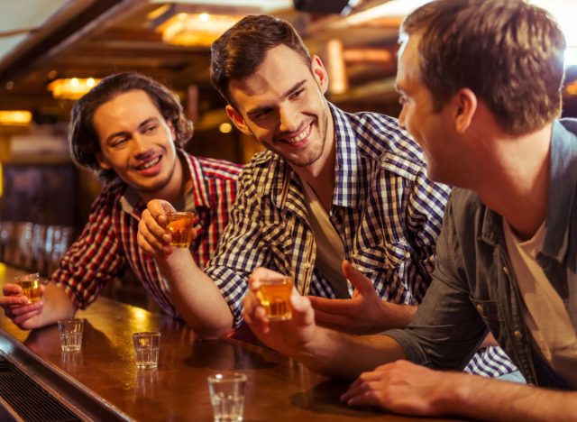 three men holding shot glasses and smiling