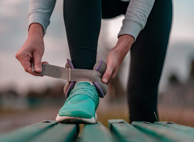 woman putting on ankle weights for walking workout