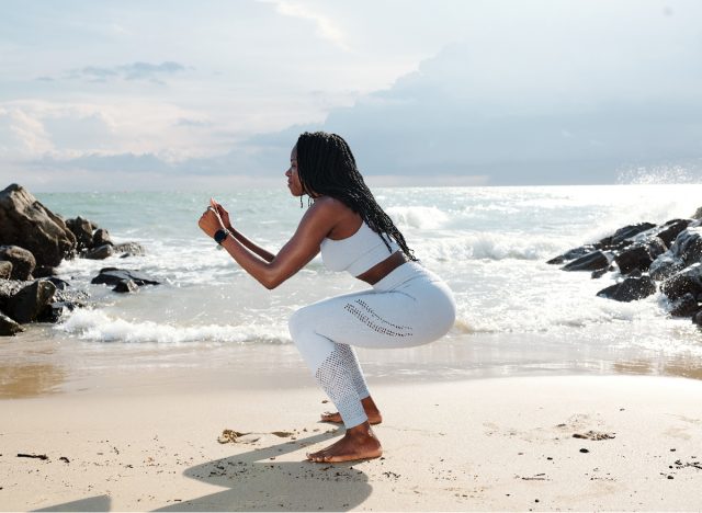 woman on beach performing deep squat stretches for weight loss