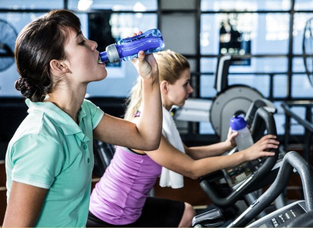 A cycling woman shows that you should drink water during your workout