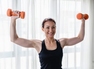 woman performing dumbbell arm workout to get rid of turkey wings