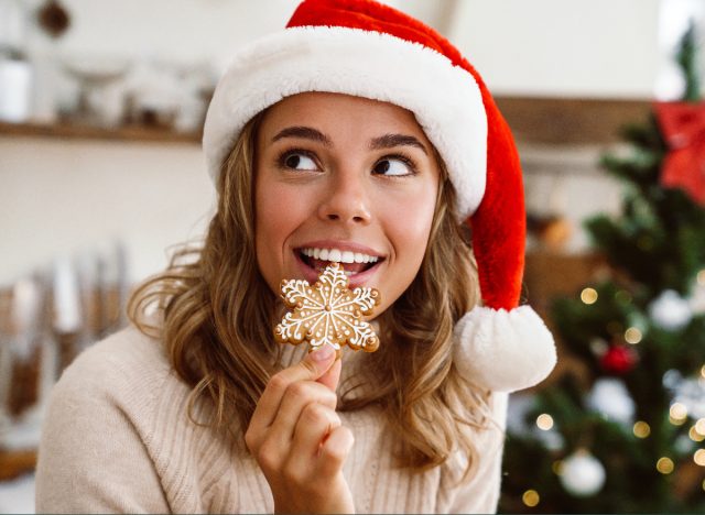 woman in santa hat eating gingerbread christmas cookie