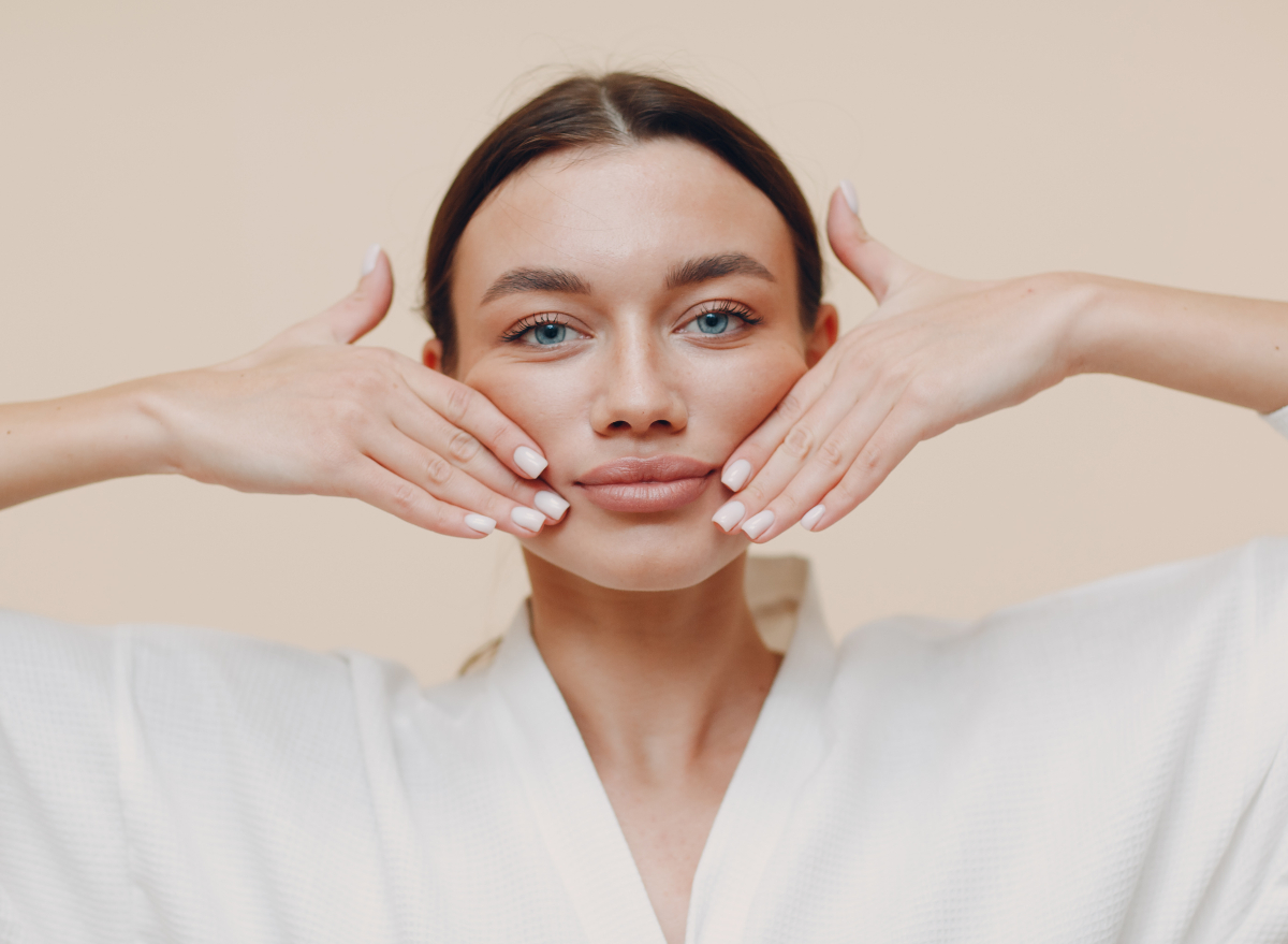 woman demonstrates face yoga to get rid of chubby cheeks