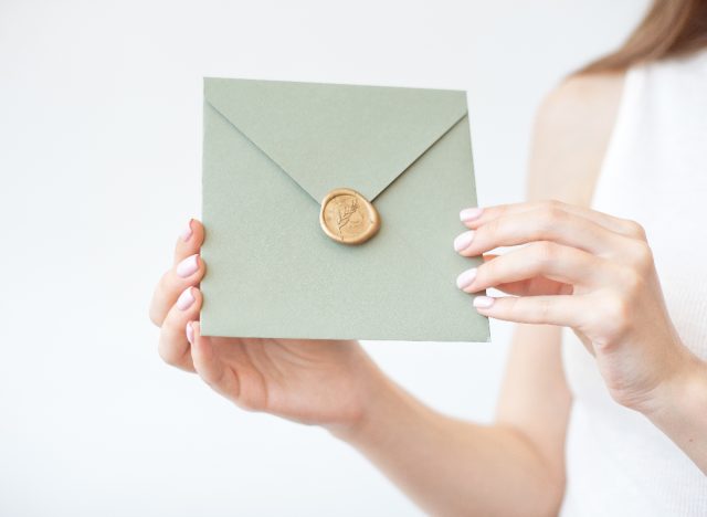 woman holding wedding invite, green envelop