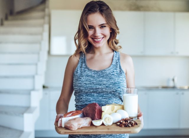 woman holds tray of protein-packed foods in kitchen