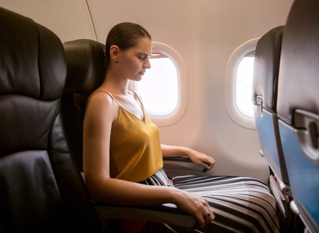 woman closes eyes experiencing in-flight travel anxiety