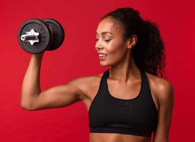 woman lifting weights, red backdrop