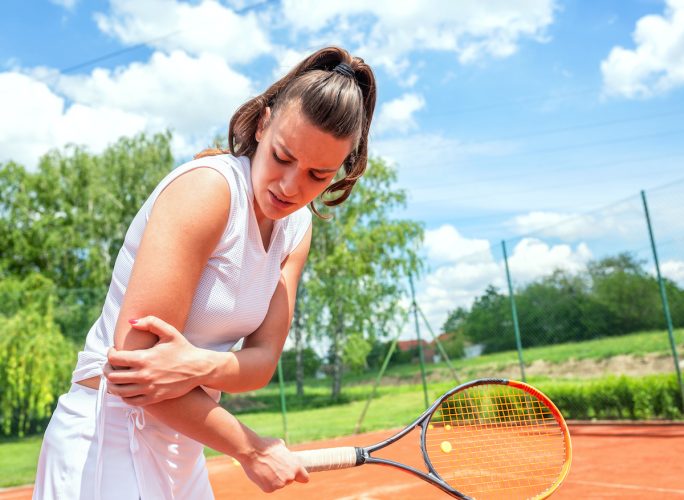 woman dealing with tennis elbow pain on the court