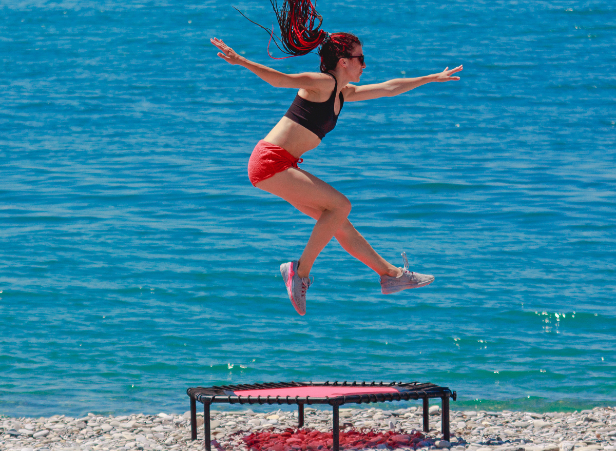 woman on beach performing trampoline exercises to build back muscle mass