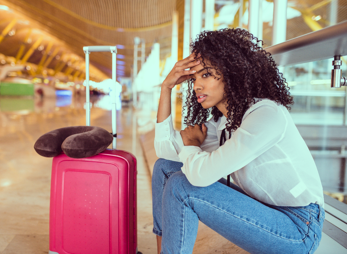 woman with pink suitcase experiencing travel anxiety at airport