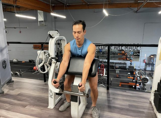 trainer working out triceps on workout machine