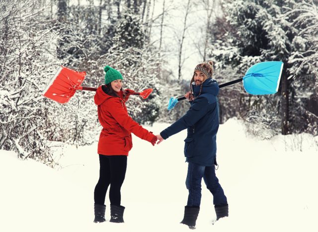 couple in snow holding snow shovels